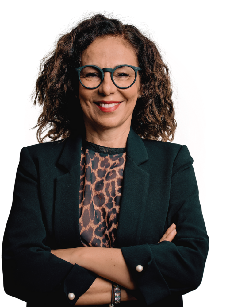 A confident woman with curly hair, wearing glasses, a dark blazer, and a leopard print top, stands with her arms crossed and smiles—exemplifying the strength of Team Performance in any workforce intelligence platform. | Humanico Workforce Intelligence Software