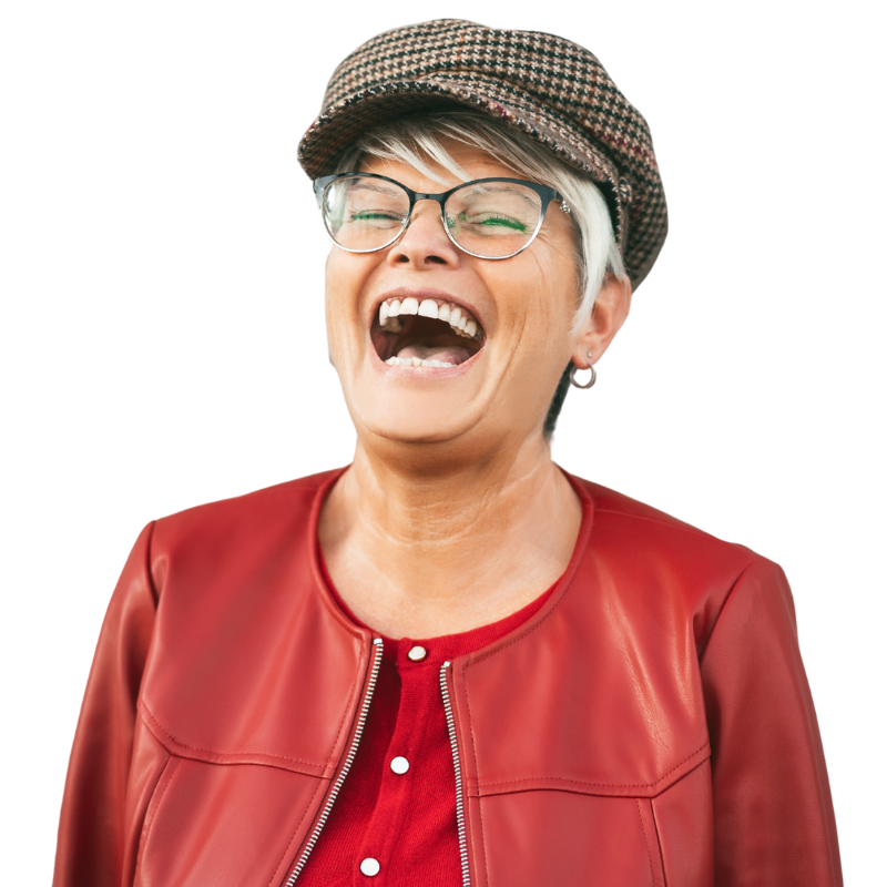 An older woman with short gray hair laughs joyfully. She wears glasses, a patterned flat cap, a red leather jacket, and a red shirt, standing against a plain background—one of the inspiring hr tech founders behind humanico. | Humanico Workforce Intelligence Software